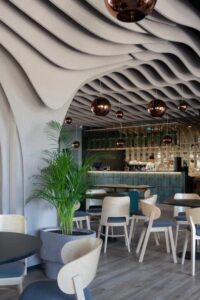 Modern restaurang med vågformad ljuddämpande takdesign och pendellampor